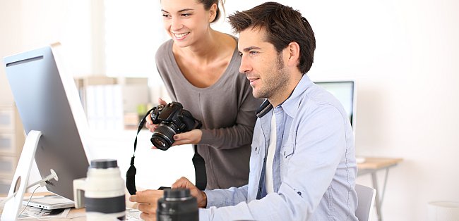 Fotograf und Fotografin sitzen vor einem PC